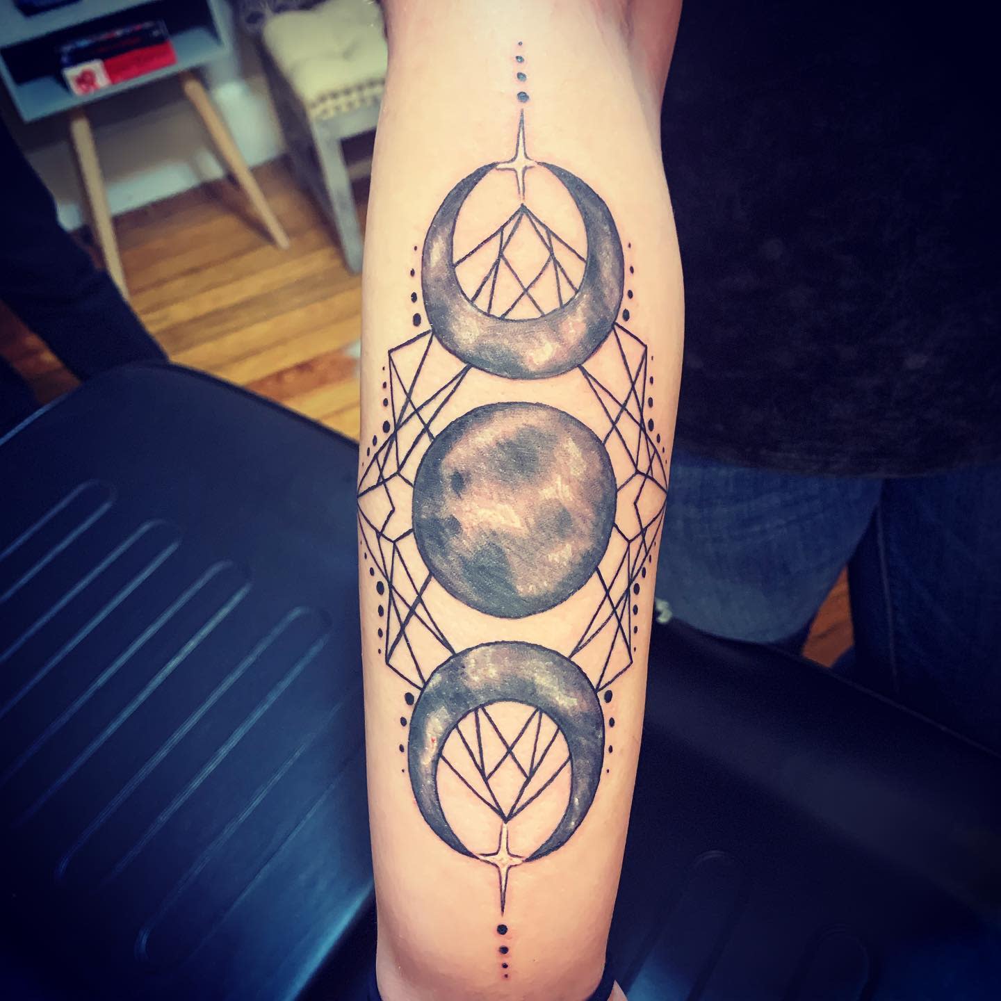 Tattoo of lunar phases with geometric designs on a forearm
